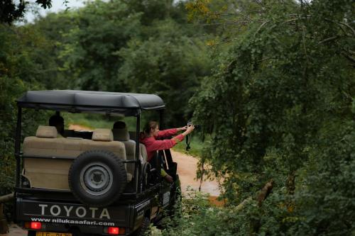a woman taking a picture of a safari vehicle at Elephant Trail in Udawalawe