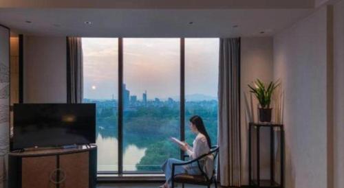 a woman sitting in a chair in front of a large window at Dajiuhua Hotel in Chizhou