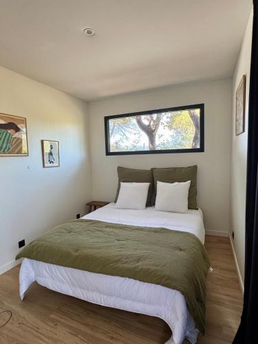 une chambre avec un grand lit avec une fenêtre dans l'établissement Lodge sous les oliviers, à Propriano