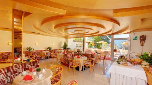 ティローロにあるHotel Tirolの大きな天井のレストラン(テーブル、椅子付)