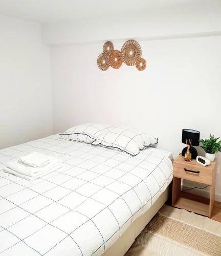 - une chambre blanche avec un lit et une table de chevet dans l'établissement T2 NEUF - 8min de Lyon - Parking privé -Terrasse, à Irigny