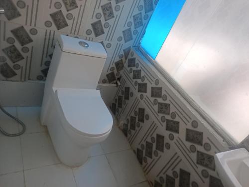 a bathroom with a toilet and a tile wall at Durbar Restro Hotel & Party Venue in Pātan