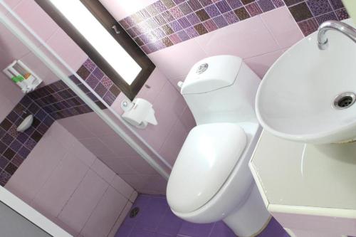 a pink bathroom with a toilet and a sink at Thanyachatra Boutique. in Phetchaburi