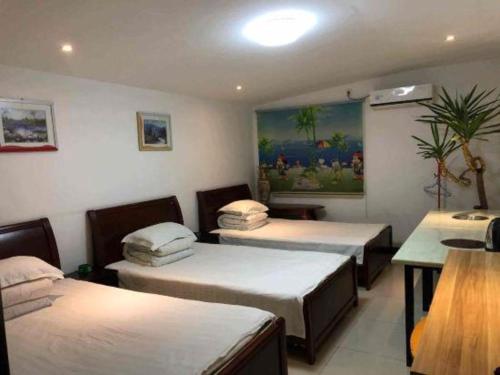 a room with three beds and a table and a painting at Lianyungang Jianyuan Hotel in Nancheng