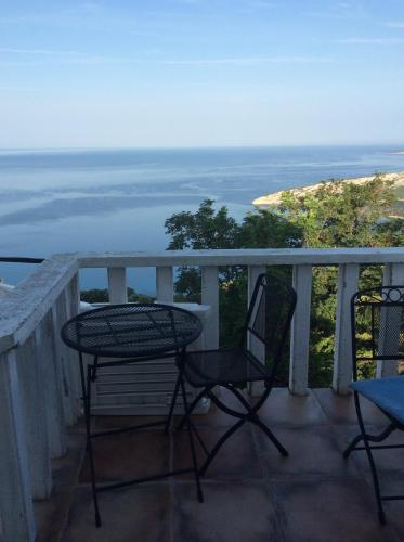 a table and two chairs on a balcony with the ocean at Apartman Ustrine in Ustrine