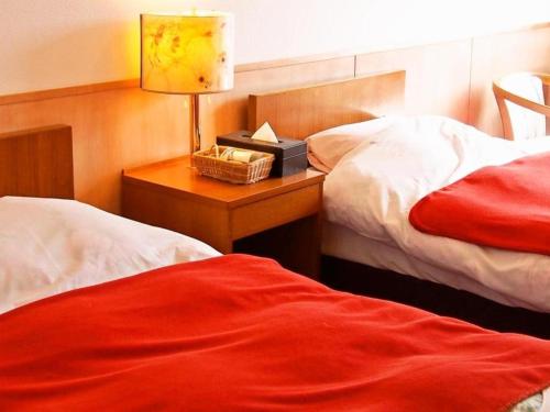 a bedroom with two beds and a table with a lamp at Espoir Misawa in Hakuba