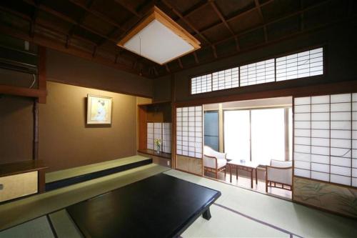a room with a table in a room with windows at Suigetsurou Hotel in Takaoka
