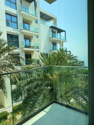 a balcony with a view of a building with palm trees at Address Beach Resort Fujairah Apartment by Blue World - 2 in Fujairah
