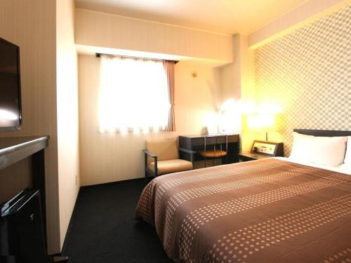 a hotel room with a bed and a chair at Hotel Livemax BUDGET Chitose in Sapporo