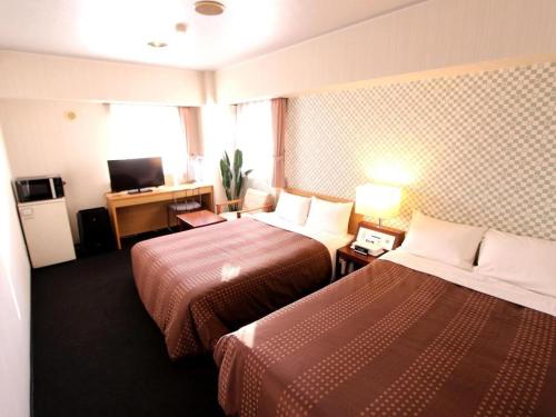 a hotel room with two beds and a television at Hotel Livemax BUDGET Chitose in Sapporo