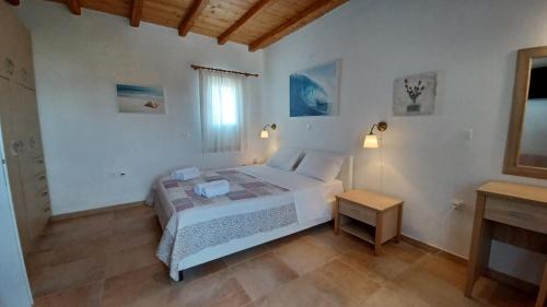 a white bedroom with a bed and a table at Blue Xenia - Villa 3 in Chrissi Akti