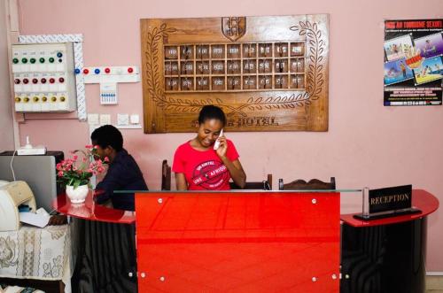 Eine Frau, die auf einem Handy an einem Tisch redet. in der Unterkunft Salama Hôtel Majunga in Mahajanga