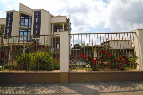 a fence in front of a building with red flowers at Hotel Doesi in Tbilisi City