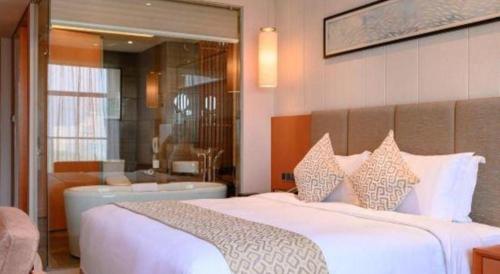 a bedroom with a large white bed and a bathroom at Suzhou Qingshan Conference Center in Suzhou