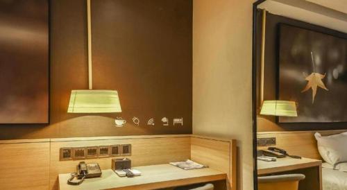 une chambre d'hôtel avec deux téléphones et un lit dans l'établissement IU Hotel Zhengzhou Wenhua Road Sanquan Road Branch, à Zhengzhou