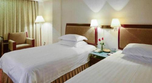a hotel room with two beds and a chair at Quanzhou Overseas Chinese Hotel in Quanzhou