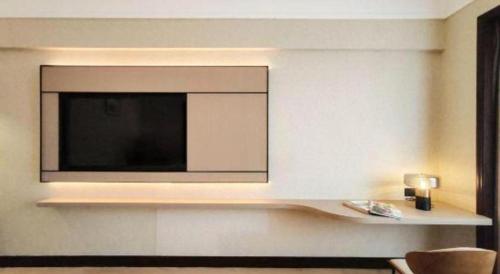a living room with a television on a wall at Fangzhong Holiday Hotel in Dongguan