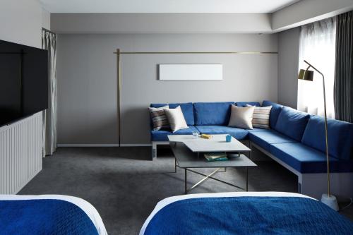 a living room with a blue couch and a table at HOTEL TORIFITO KANAZAWA in Kanazawa