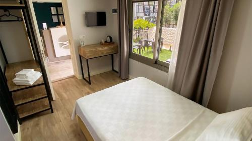 a bedroom with a bed and a mirror and a window at Sahil Otel in Cesme