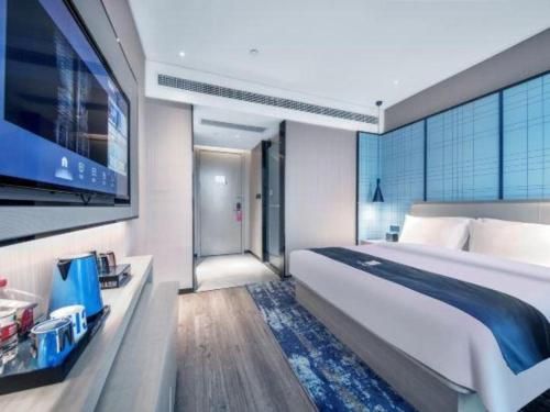 a bedroom with a large bed and a flat screen tv at Echarm Hotel Xiangyang Erqi in Xiangyang
