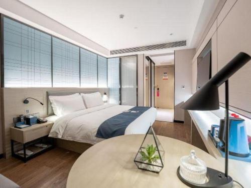 a bedroom with a bed and a table with a lamp at Echarm Hotel Xiangyang Erqi in Xiangyang
