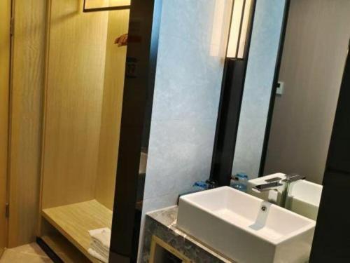 a bathroom with a white sink and a mirror at Echarm Hotel Xiangyang Erqi in Xiangyang