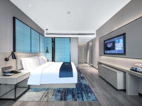 a bedroom with a large bed and a flat screen tv at Echarm Hotel Xiangyang Erqi in Xiangyang