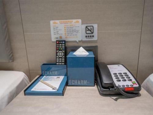 a phone sitting on a bed next to a box at Echarm Hotel Xiangyang Erqi in Xiangyang