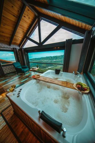 a large bath tub in a room with a large window at Lazivilla Suit Dağ Evi in Rize