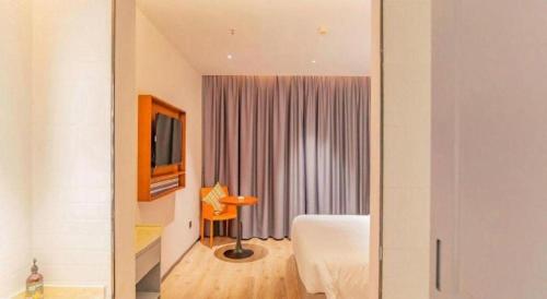 a hotel room with a bed and a tv and a room at City Comfort Premier Hotel Xiaogan Anlu Railway Station Dongda Times Square in Xiaogan
