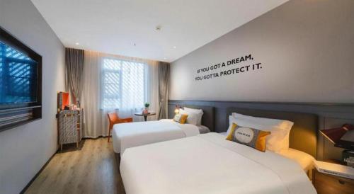 a hotel room with two beds and a sign on the wall at City Comfort Premier Hotel Xiaogan Anlu Railway Station Dongda Times Square in Xiaogan