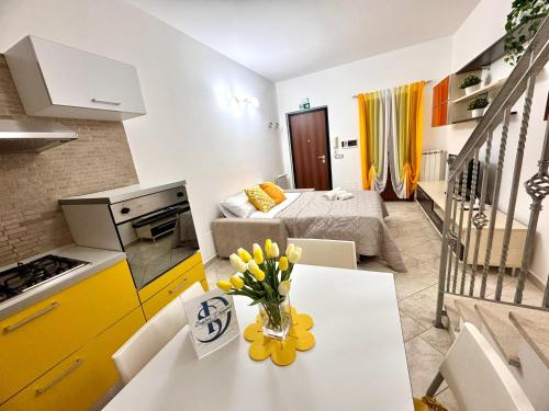 a kitchen and a living room with a table with flowers on it at Suites Dreams Fiumicino Sole in Fiumicino