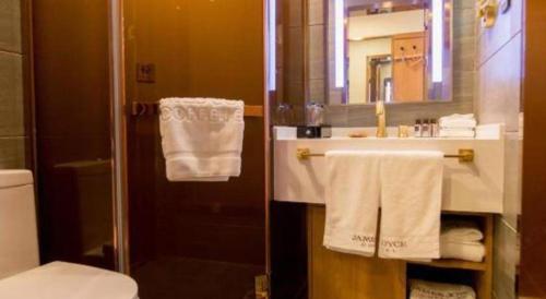 a bathroom with a shower and a sink with towels at James Joyce Coffetel Harbin Central Street in Harbin