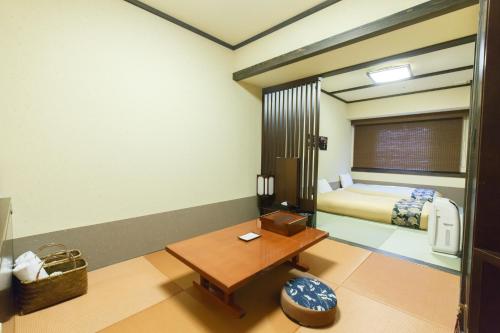 a room with a bedroom with a bed and a table at Takayama Ouan in Takayama