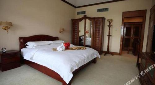 a bedroom with a bed with a stuffed animal on it at Kunming Dianchi Garden Hotel & Spa in Kunming