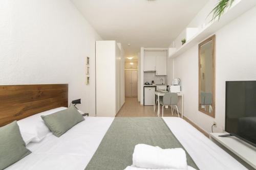 a white bedroom with a large bed and a television at Classy VII - Ferga Suites in Madrid