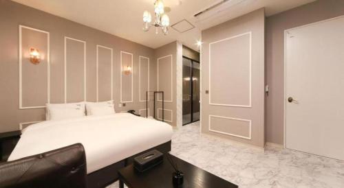 a bedroom with a white bed and a black chair at Hotel Seowa in Gimhae