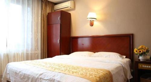 a bedroom with a large bed with white sheets at GreenTree Inn Harbin Central Avenue in Harbin