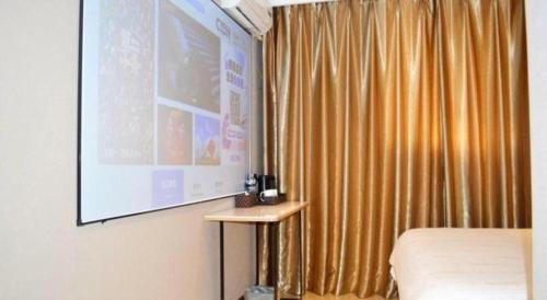 a room with a large projection screen next to a bed at GreenTree Inn Harbin Central Avenue in Harbin