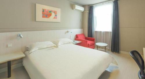 a bedroom with a white bed and a red chair at Jinjiang Inn Luoyang Wangcheng Park Metro Station in Luoyang