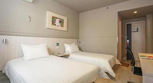a hotel room with two beds and a table at Jinjiang Inn Luoyang Wangcheng Park Metro Station in Luoyang