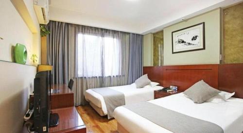 a hotel room with two beds and a television at Hangzhou Bokai Westlake Hotel in Hangzhou