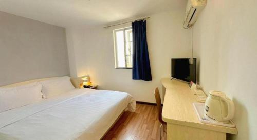 a bedroom with a bed and a desk with a computer at 7 Days Inn Guangzhou Zoo Huanghuagang Metro Station in Guangzhou