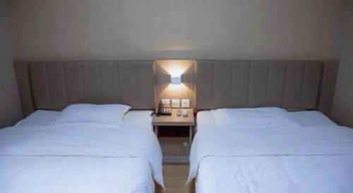 two beds in a hotel room with white sheets at 7 Days Inn Qingdao Si Liu South Road in Qingdao