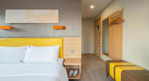 a bedroom with a white bed and a yellow headboard at 7 Days Premium Xi'an Dayan Tower Xiaozhai Metro Station in Xi'an