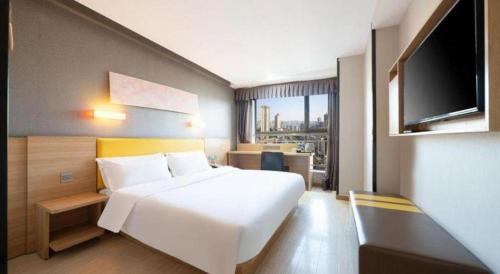 a bedroom with a white bed and a flat screen tv at 7 Days Premium Xi'an Dayan Tower Xiaozhai Metro Station in Xi'an