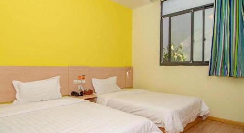 two beds in a room with yellow walls and a window at 7 Days Inn Suzhou Wangting Pearl Commercial Plaza in Suzhou