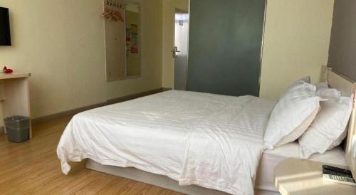 a bedroom with a bed with white sheets and pillows at 7 Days Inn Hami Baofeng Market in Qumul