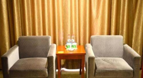 two chairs and a table in a room with curtains at GreenTree Inn Xian Longshouyuan Subway Station Business Hotel in Xi'an