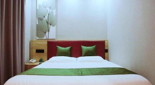 a bedroom with a bed with a red headboard and green pillows at GreenTree Inn Nanjing Confucius Temple Sanshan Street Subway Station Express Hotel in Nanjing